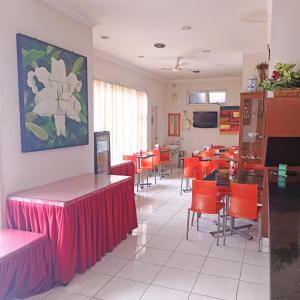 a dining room with tables and red chairs at Hotel Flamboyan in Jember