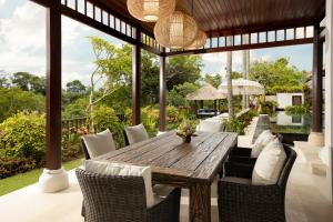 an outdoor dining room with a wooden table and chairs at Villa Ken Jimbaran by Nakula in Jimbaran