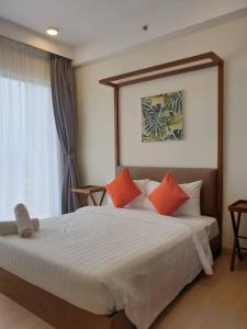 a bedroom with a large white bed with orange pillows at Studio with Privacy Balcony and NETFLIX at TimurBay Sea Front Residence in Kuantan