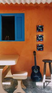 Une guitare est assise à côté d'un mur avec un tabouret dans l'établissement Sintonia Surf Hostel e Bar, à Ubatuba