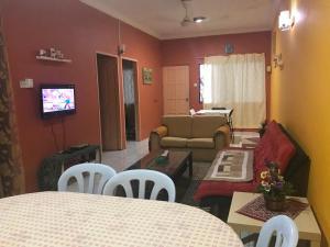 Kota SamarahanにあるDesa Ilmu Homestayのリビングルーム(ソファ、テーブル、椅子付)
