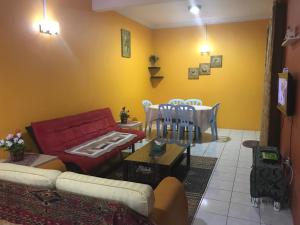 sala de estar con sofá rojo y mesa en Desa Ilmu Homestay en Kota Samarahan