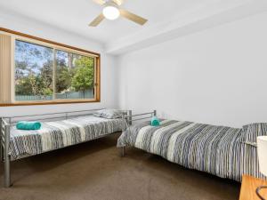 two beds in a room with a window at Southern Escape by Experience Jervis Bay in Sanctuary Point