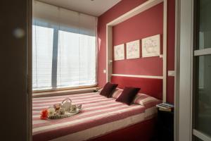 sypialnia z łóżkiem z czerwonymi ścianami i oknem w obiekcie Beach House,Giardino,Piscina,Spiaggia, 6 posti w Viareggio +6 zdjęć