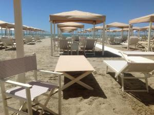 a beach with chairs and tables and umbrellas at Beach House,Giardino,Piscina,Spiaggia, 6 posti in Viareggio
