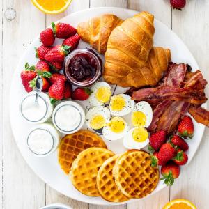 - un plateau de petit-déjeuner composé d'œufs, de gaufres et de fraises dans l'établissement Hgl Guest House, à East Legon