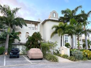 a building with palm trees in a parking lot at Sago Garden Apartment at Royal Westmoreland in Saint James