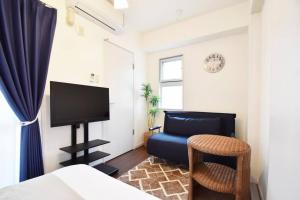 Schlafzimmer mit einem Bett, einem TV und einem Stuhl in der Unterkunft enジョイマールひろ 401 in Tomari