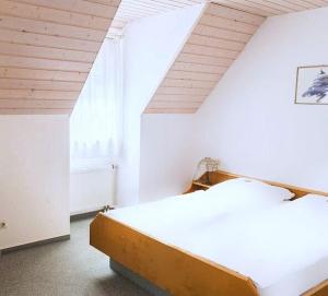 a white bedroom with a bed and a window at Engelhof in Weilheim an der Teck