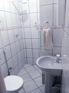 a white bathroom with a toilet and a sink at SUITES COR DO SOL TRINDADE in Trindade