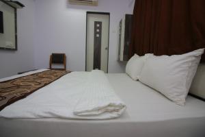 een bed met witte lakens en kussens in een kamer bij Hotel Apex in Navi Mumbai