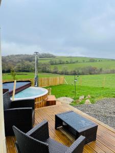 una terraza con mesa, sillas y piscina en Private country caravan surrounded by fields en Liskeard