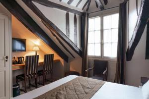 una camera con un letto e due sedie e una scrivania di Hotel Saint-Louis Marais a Parigi