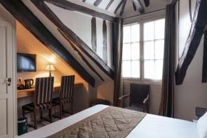 a bedroom with a bed and two chairs and a desk at Hotel Saint-Louis Marais in Paris
