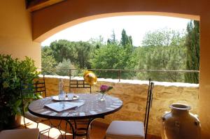 a table and chairs on a balcony with a window at Hostellerie Le Roy Soleil in Ménerbes