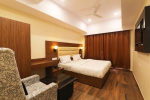 een hotelkamer met een bed en een stoel bij FabHotel Blueark in Lucknow