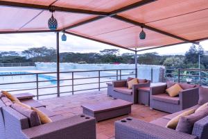 a patio with chairs and tables and a view of the water at Alphas Homestay in Naivasha