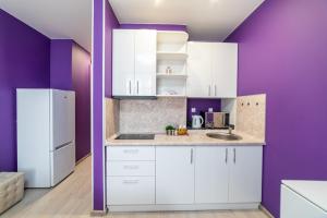 a kitchen with white cabinets and purple walls at "Sharm" Стильная студия на Броско in Khabarovsk
