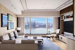 a living room with a couch and a large window at Four Seasons Hotel Hong Kong in Hong Kong