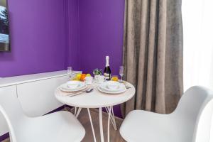 una mesa blanca con 2 sillas blancas y una botella de vino en "Sharm" Стильная студия на Броско, en Khabarovsk