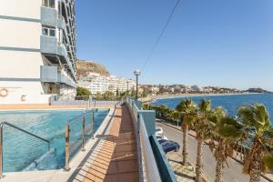 a balcony of a building with a pool and palm trees at Apartment with sea view in Almuñécar