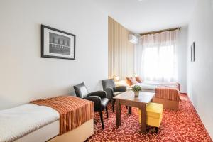 a hotel room with two beds and a table and chairs at Hotel U Zlatého kohouta in Kroměříž