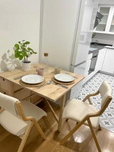 a wooden table with plates and chairs in a kitchen at Precioso Apartamento recién reformado en centro in Aranjuez