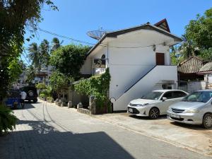 two cars parked in front of a white building at Beach Walk Hotel Unawatuna in Unawatuna