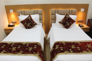 2 bedden in een hotelkamer met witte lakens en kussens bij S R Continental in Gulbarga