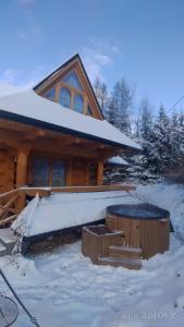 a log cabin in the snow in front of a house at Przystań w Tatrach - Przytulne Domki i Apartamenty-Luxury Chalets and Apartments in Bukowina Tatrzańska