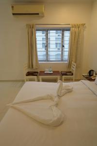 a large white bed in a room with a window at Hotel Palmyra Grand Inn in Tirunelveli