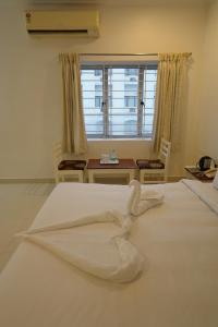 a large white bed in a room with a window at Hotel Palmyra Grand Inn in Tirunelveli
