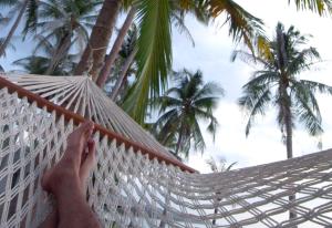 a person laying in a hammock in front of palm trees at Jasmine & Tea House in Mae Nam