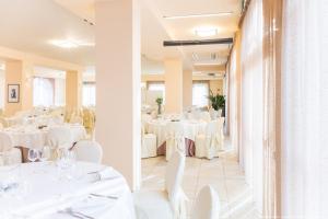 Trissino的住宿－Sirio Life Hotel，用餐室配有白色的桌子和白色的椅子