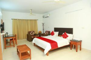 a bedroom with a large white bed and a couch at KTDC Tamarind in Kondotti