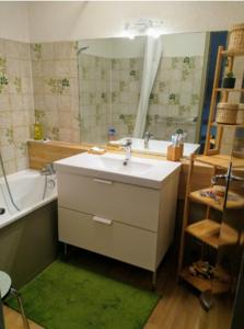 ein Badezimmer mit einem Waschbecken, einer Badewanne und einem Spiegel in der Unterkunft Residence Pierre Aigue in Saint-Sorlin-dʼArves