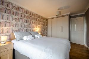 um quarto com uma cama branca e uma parede de livros em Platform West Hull House em Hull