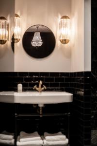 a bathroom with a sink and a mirror and lights at Boutique Hotel Huys Oud Teylingen in Warmond