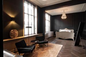 - un salon avec des murs noirs, un canapé et des chaises dans l'établissement Boutique B&B Huys Oud Teylingen, à Warmond