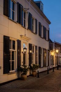 een gebouw met ramen en bloempotten in een straat bij Boutique B&B Huys Oud Teylingen in Warmond