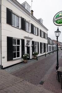 a white building with black shutters on a street at Boutique Hotel Huys Oud Teylingen in Warmond