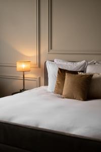 a bed with white sheets and pillows and a lamp at Boutique Hotel Huys Oud Teylingen in Warmond