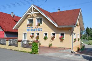 un bâtiment avec des fleurs sur son côté dans l'établissement Penzion Mirabel, à Bešeňová