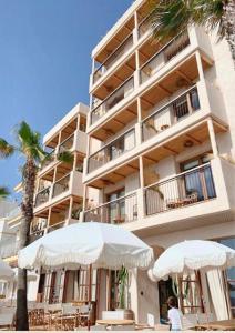 un gran edificio con dos sombrillas delante en Nomad Hotel - Xábia Port, en Jávea