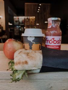 a table with a sandwich and a cup of sauce and an apple at Comfort Hotel Xpress Youngstorget in Oslo +37 photos
