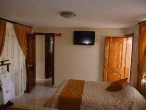 a bedroom with a bed and a television on the wall at Hostal Fevilamir in Ibarra