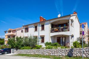 a large white building with a stone wall at Apartment Mužić in Cres