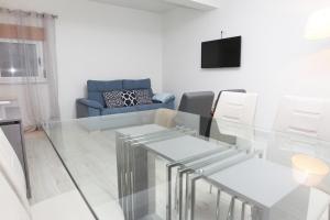 sala de estar con mesa de cristal y sofá azul en Miranda Tradicional, en Miranda do Douro