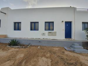 um grande edifício branco com uma porta azul e janelas em Casa ERIZO em Caleta de Sebo