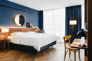 una camera da letto con un letto, una scrivania e uno specchio di Hotel Gilbert a Vienna